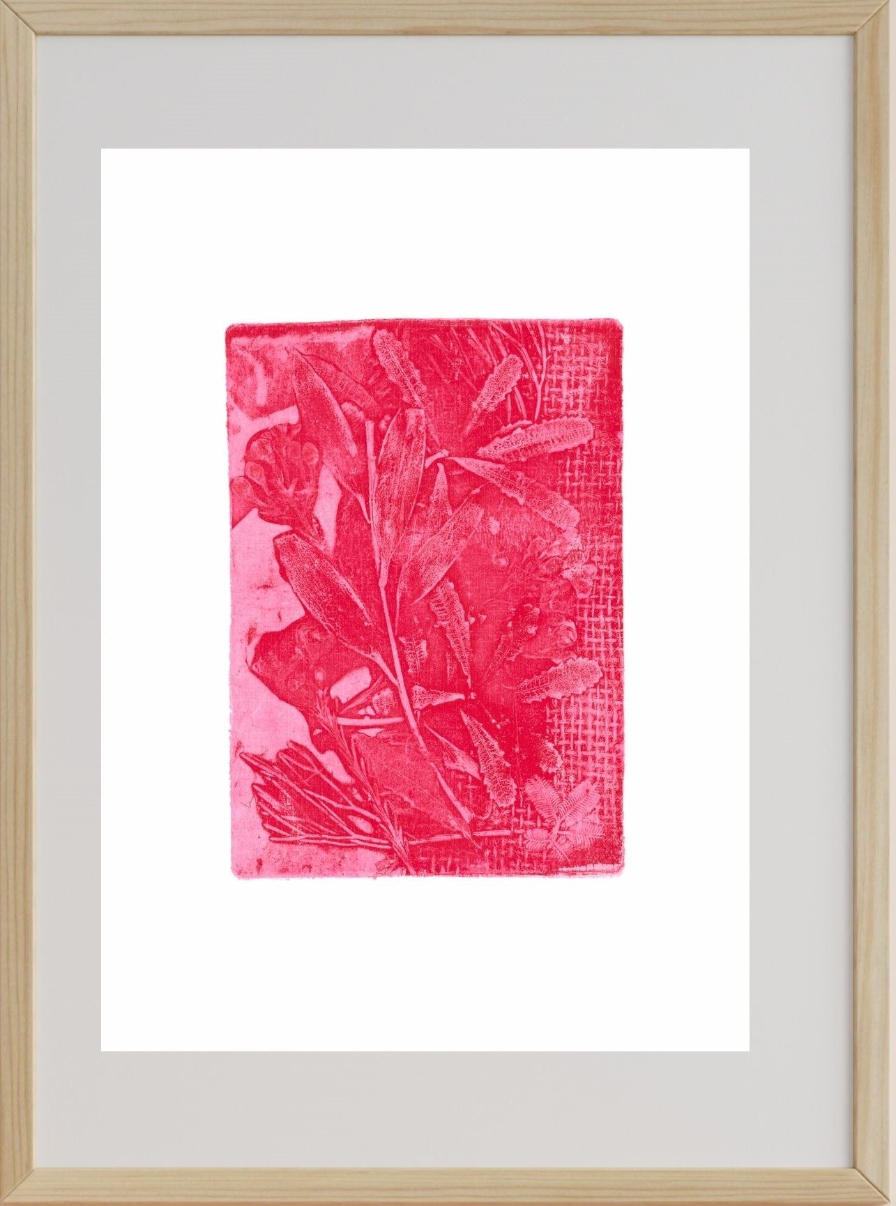 A framed artwork featuring a pink gel monoprint with botanical patterns, set against a white background.