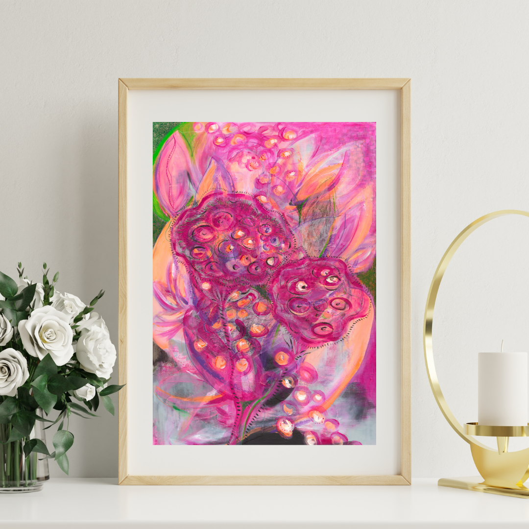 Framed abstract artwork with pink and purple hues on a white wall, next to a vase of flowers and a candle.