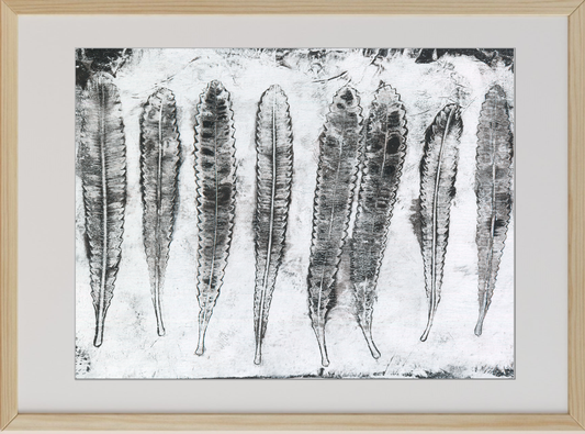 Framed black and white artwork of leaf-like shapes on a textured background